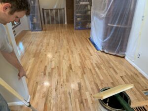 Our team working on adding a finish to light brown hardwood floors