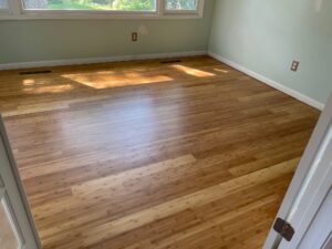 Medium brown hardwood floors, newly installed, reflecting light from a window