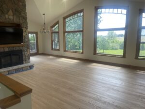 light brown hardwood floors in front of large, open windows letting in natural light
